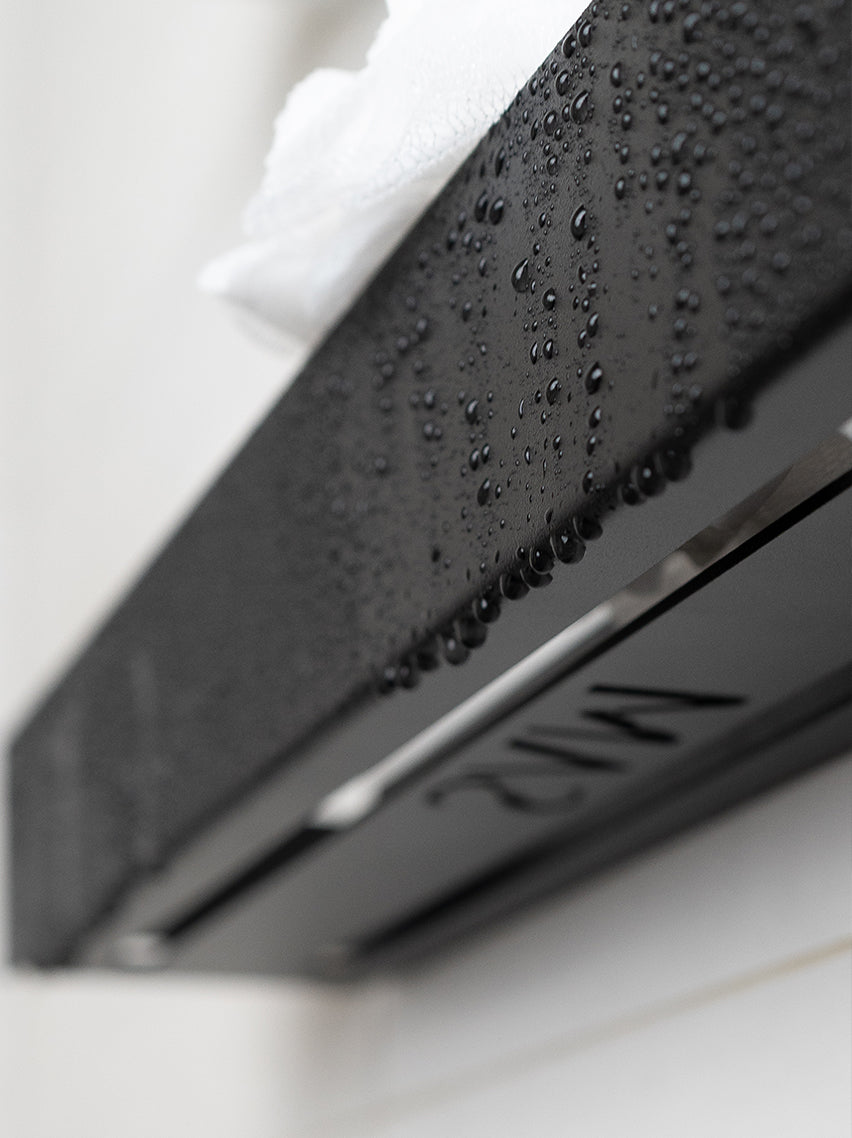 Close Up eines Duschregals von SAM, an welchem Wassertropfen abperlen. Das Foto zeigt das Duschregal schräg von unten, welches die Ausschnitte zeigen durch welche das Wasser gut ablaufen kann.