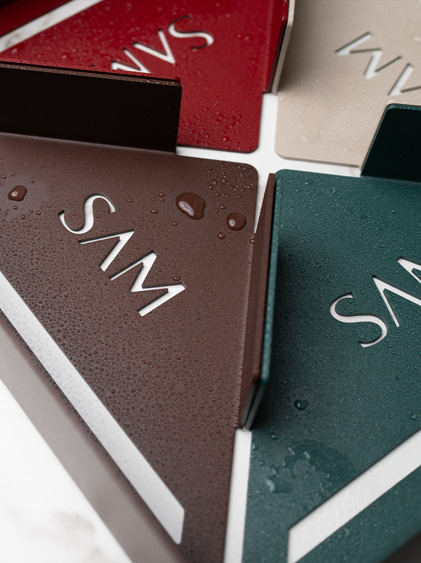 Duschregal Montecarlo in der Draufsischt im Close Up in verschiedenen Designer Farben: Marone, Velvet Red, Champagner und Sparkling Green. Wassertropfen perlen auf der Pulverbeschichteten Metalloberfläche ab.