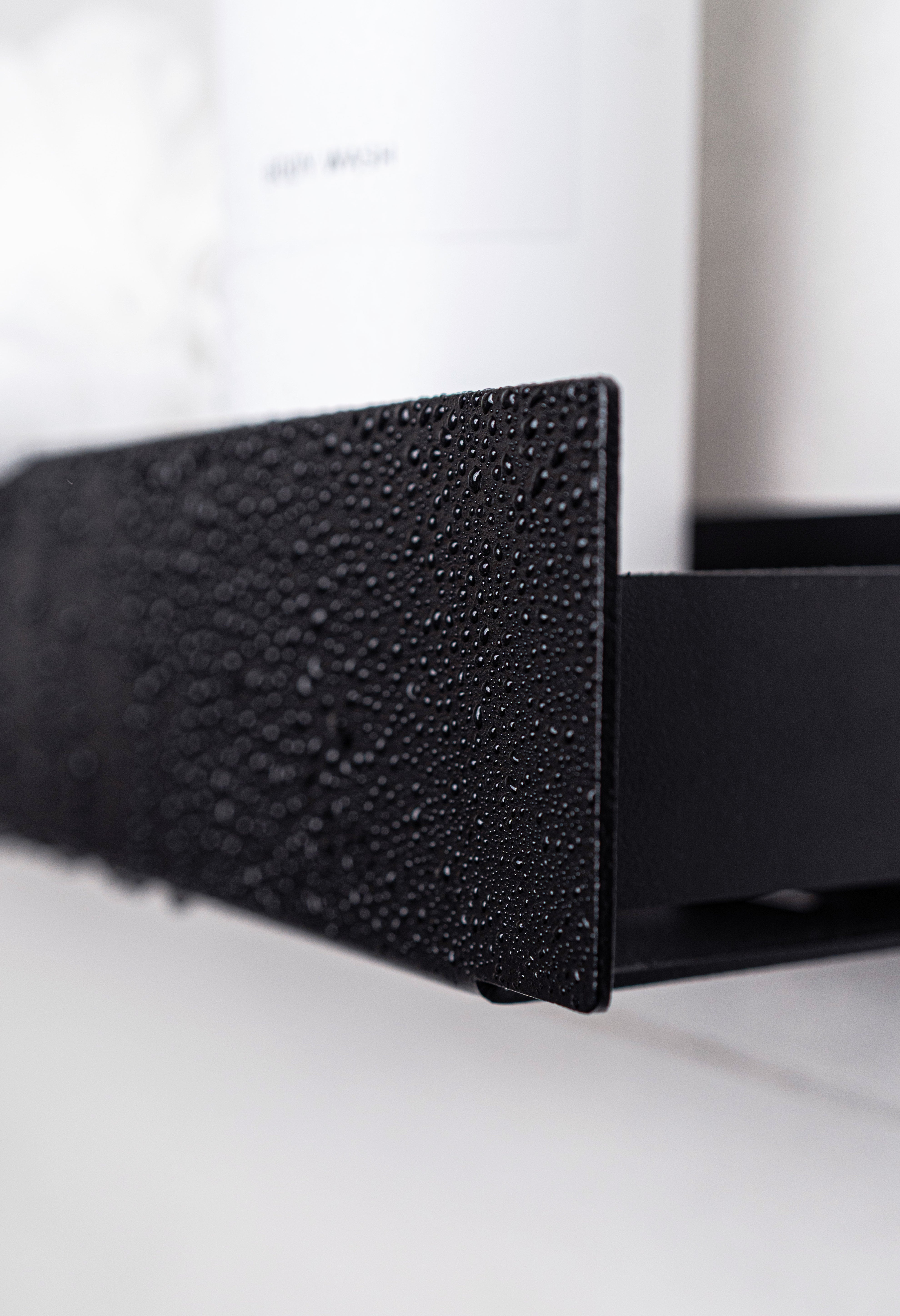 CLose-Up der Design-Duschablage KORSIKA aus Metall in schwarz. Wassertropfen perlen ab.