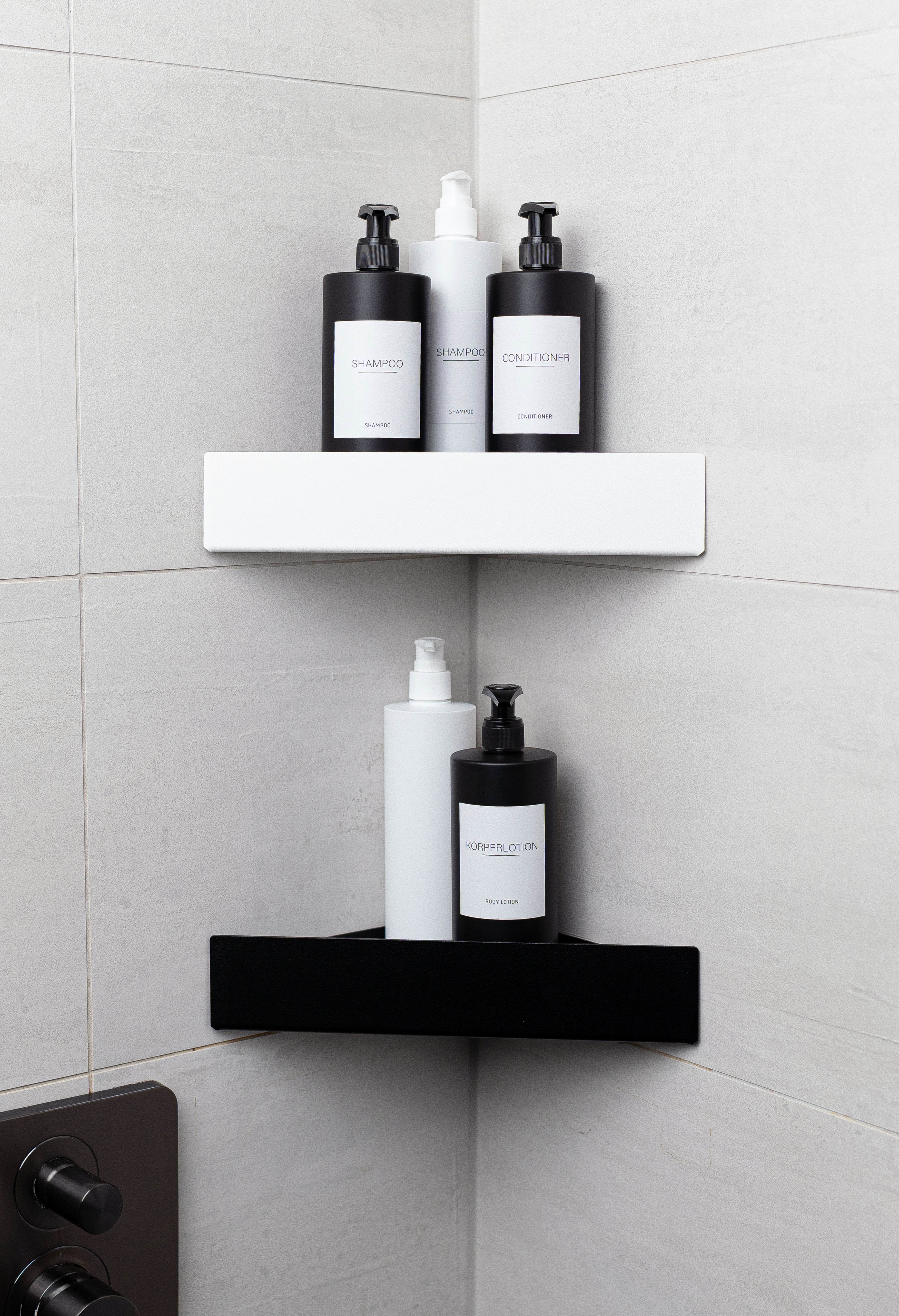 Duschablgen Monte Carlo zum Kleben ohne Bohren in den Farben Schwarz und weiß in frontaler Ansicht in Ecke der Dusche montiert mit passenden modernen Pumpflaschen dekoriert