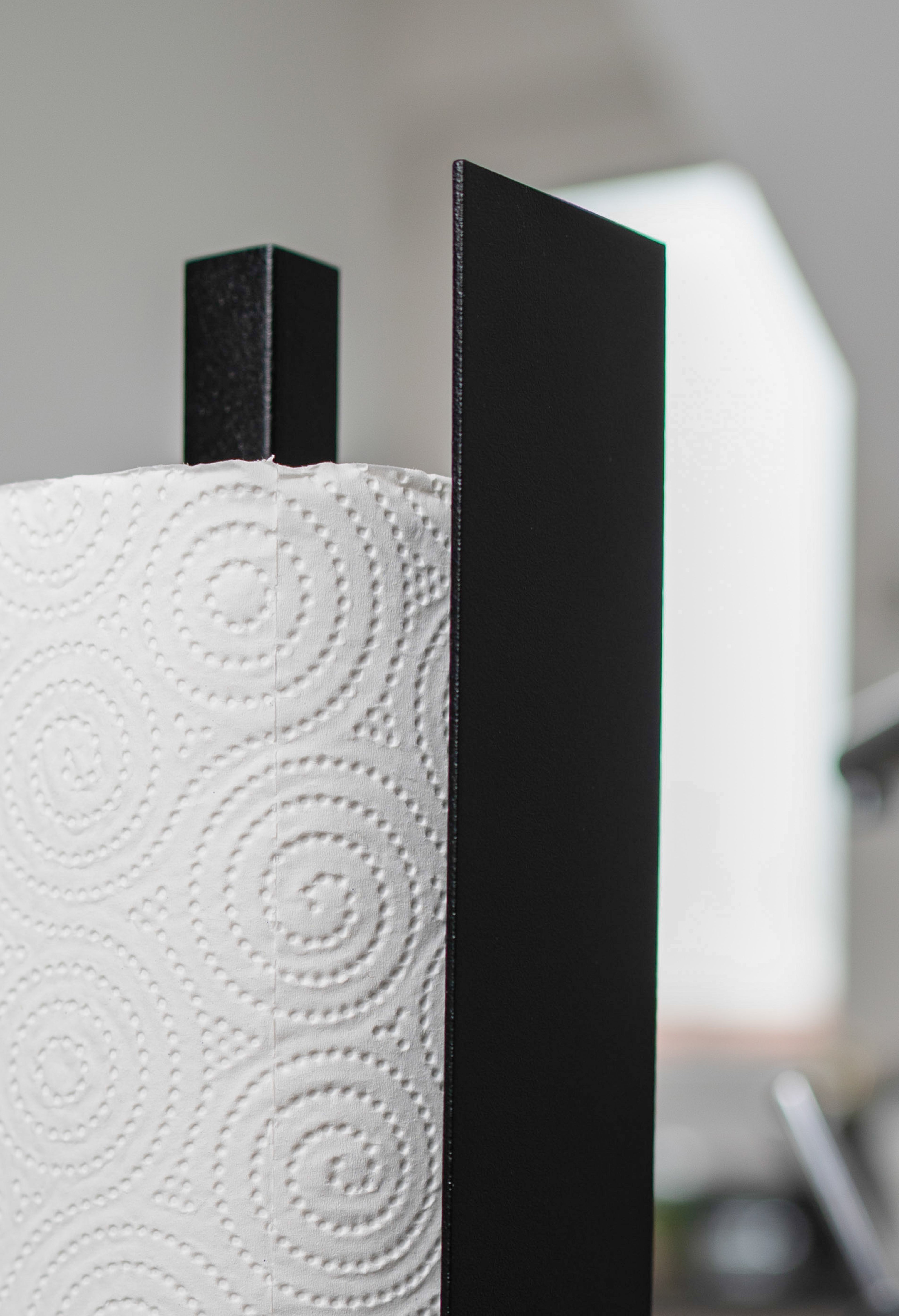 Deatilaufnahme Küchenrollenhalter Granada pulverbeschichtet in matt schwarz auf einer dunklen Marmorarbeitsfläche in einer hellen Küche