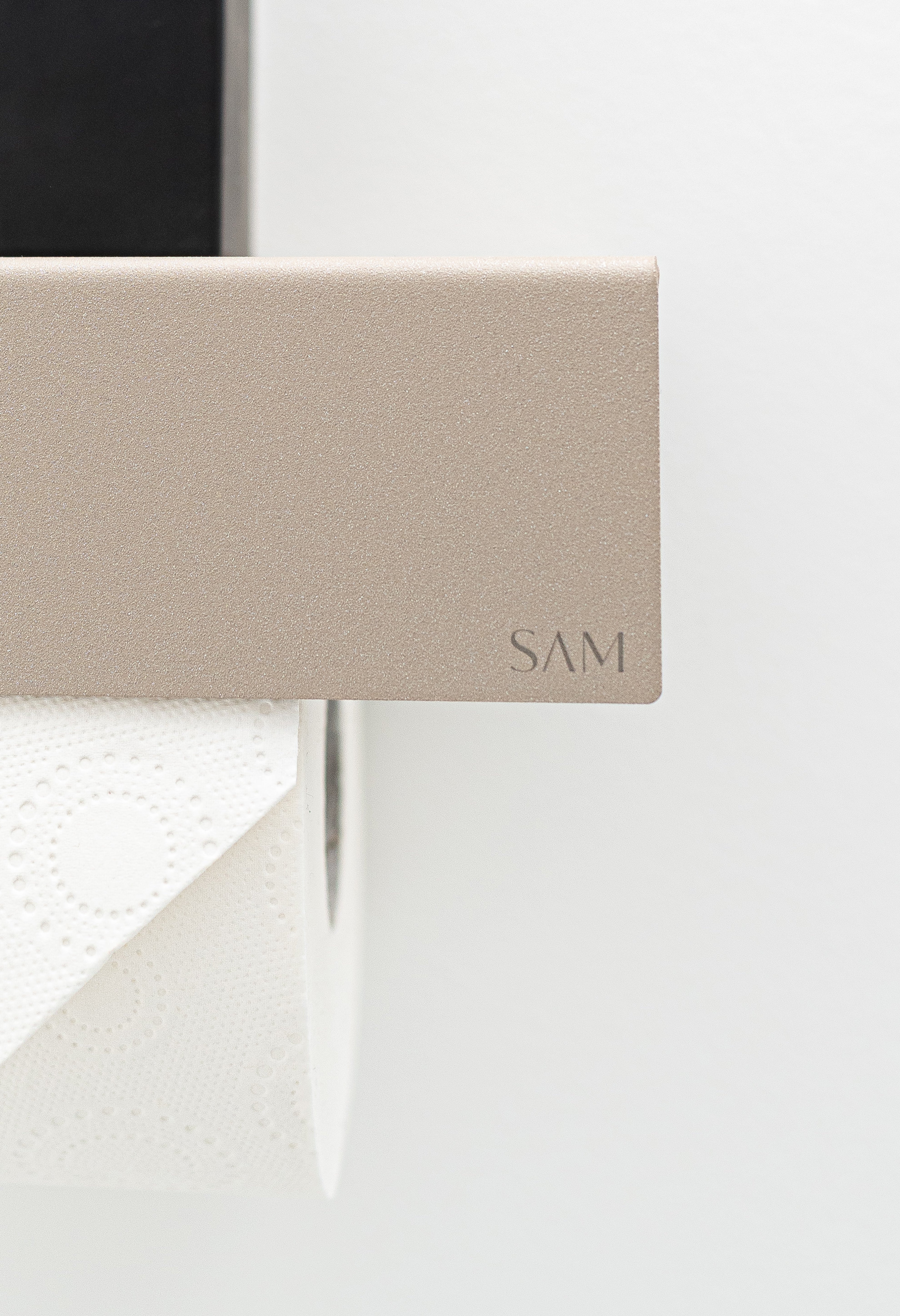 Toilettenpapierhalter LILLE zum Kleben ohne Bohren Close Up Frontal um kante und gelasertes kleines SAM Logo an rechter Frontblende zu zeigen.