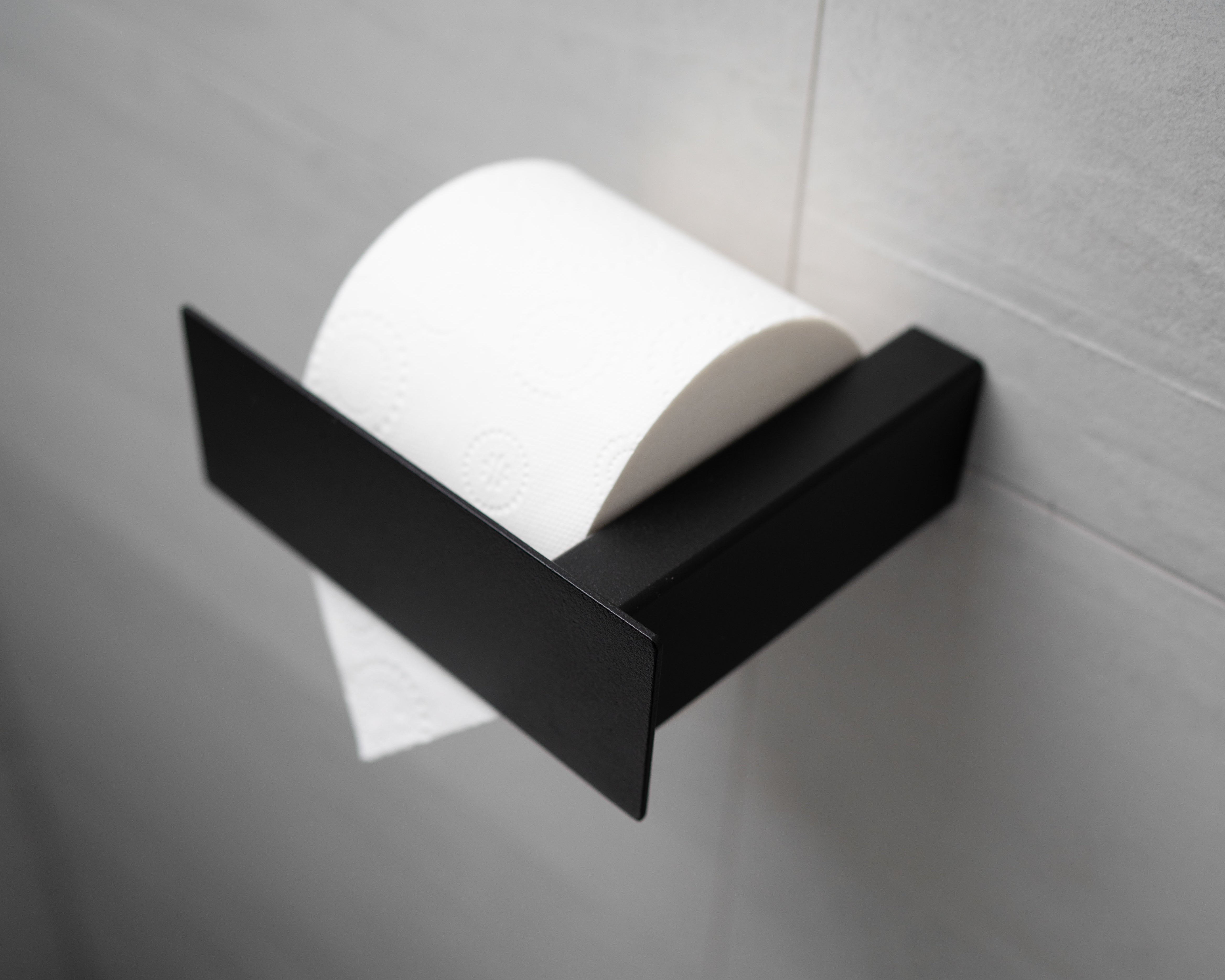 Schwarzer pulverbeschichteter Toilettenpapierhalter aus Metall mit Blende in schräger Ansicht.