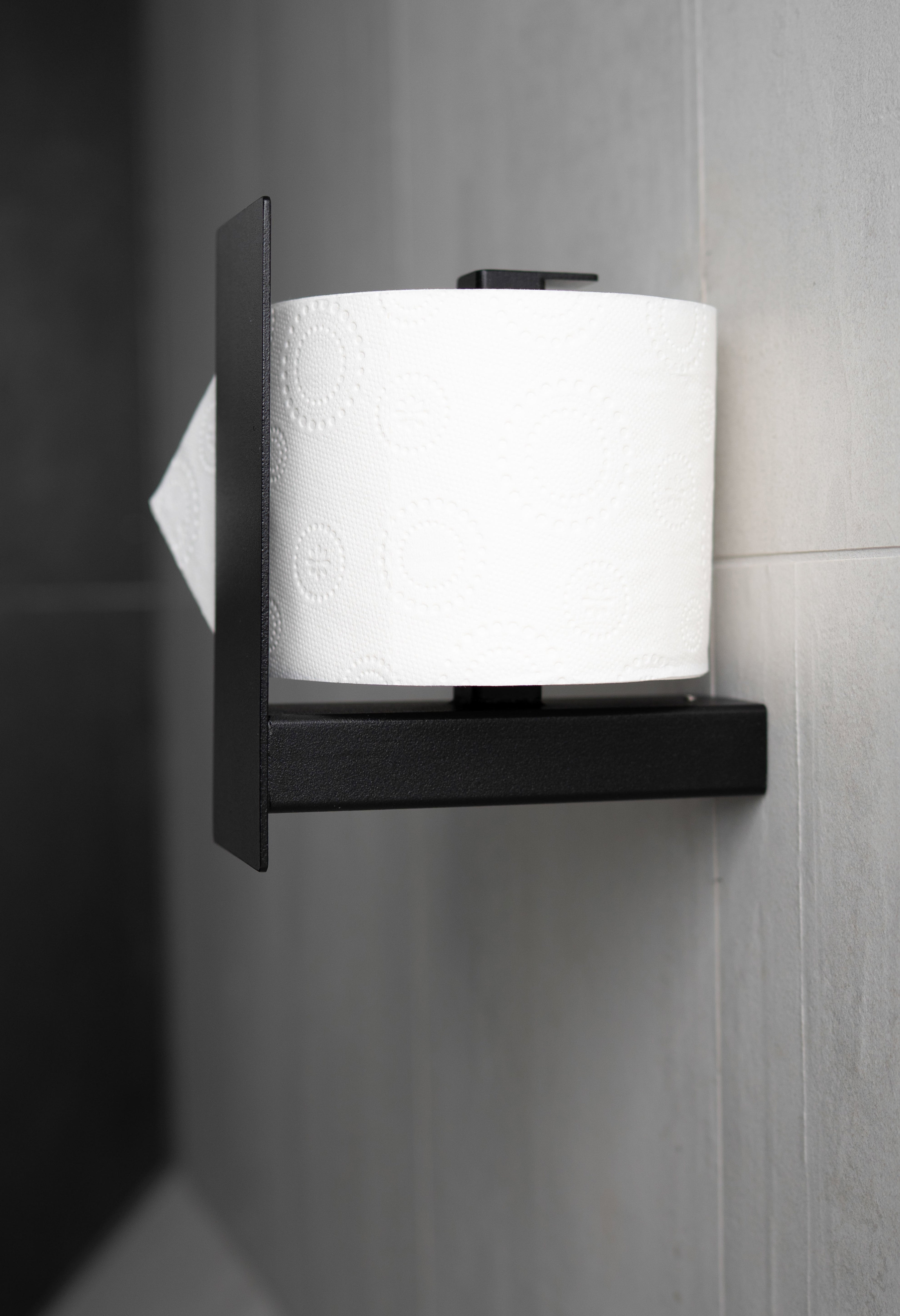 Schwarzer pulverbeschichteter Toilettenpapierhalter aus Metall mit Blende in Ansicht von oben.