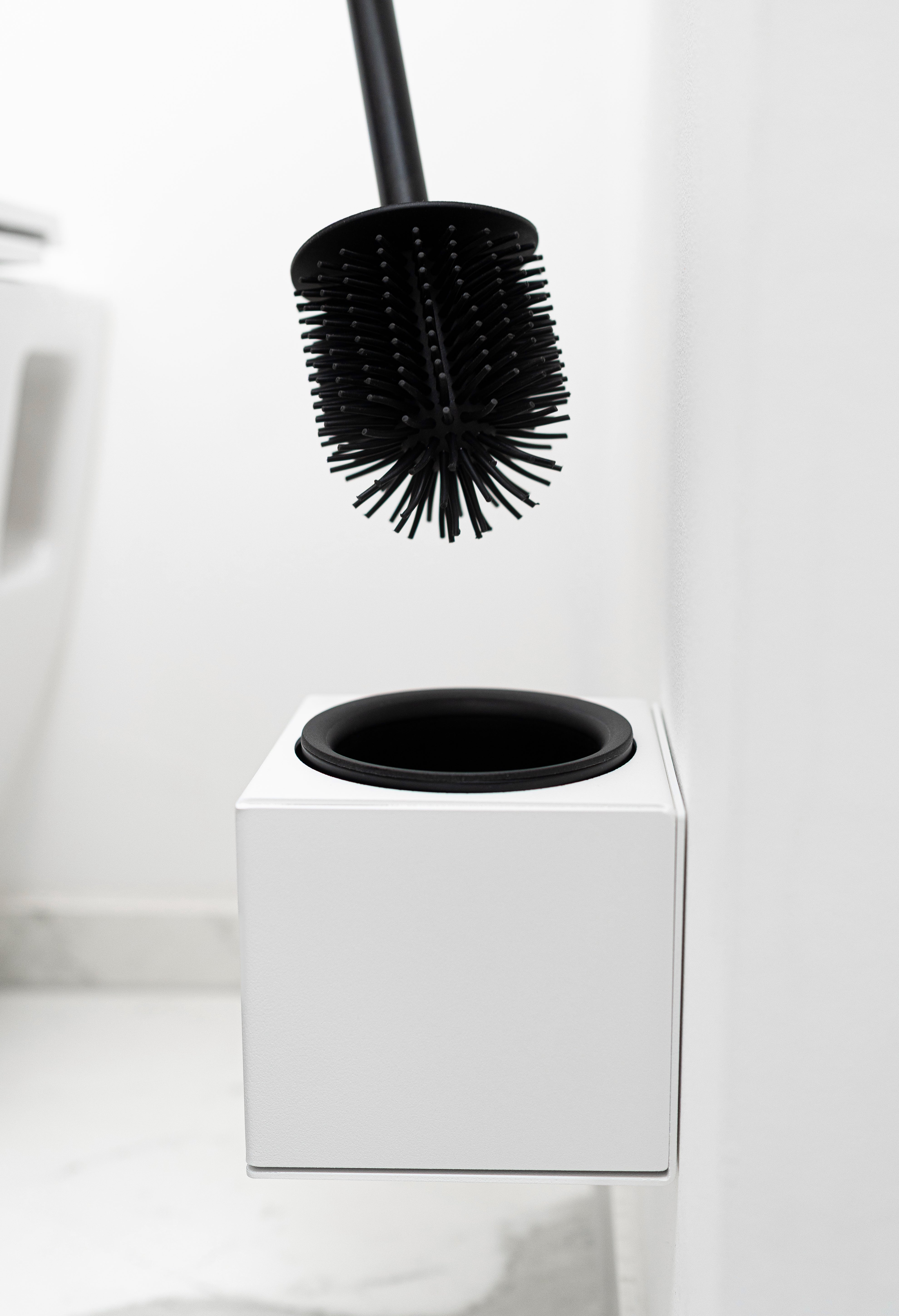 WC-Bürstenhalter LYON zum Kleben ohne Bohren in Farbe Weiß Close Up von WC Bürste in farbe schwarz die aus Halterung herausgezogen wird