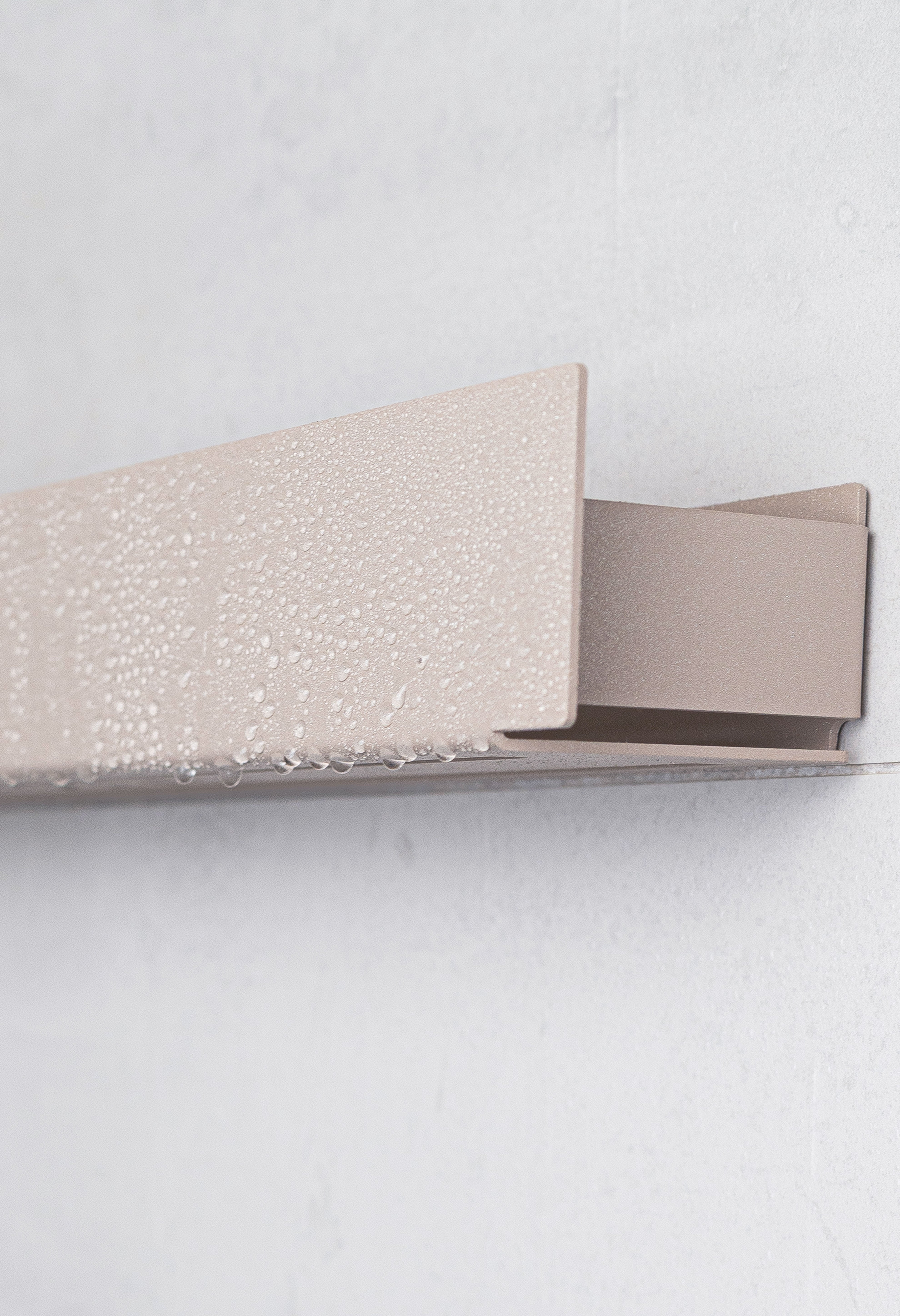 Close Up seitliche Kante Duschablage Korsika zum Kleben in Farbe Champagner. Wassertropfen perlen ab.