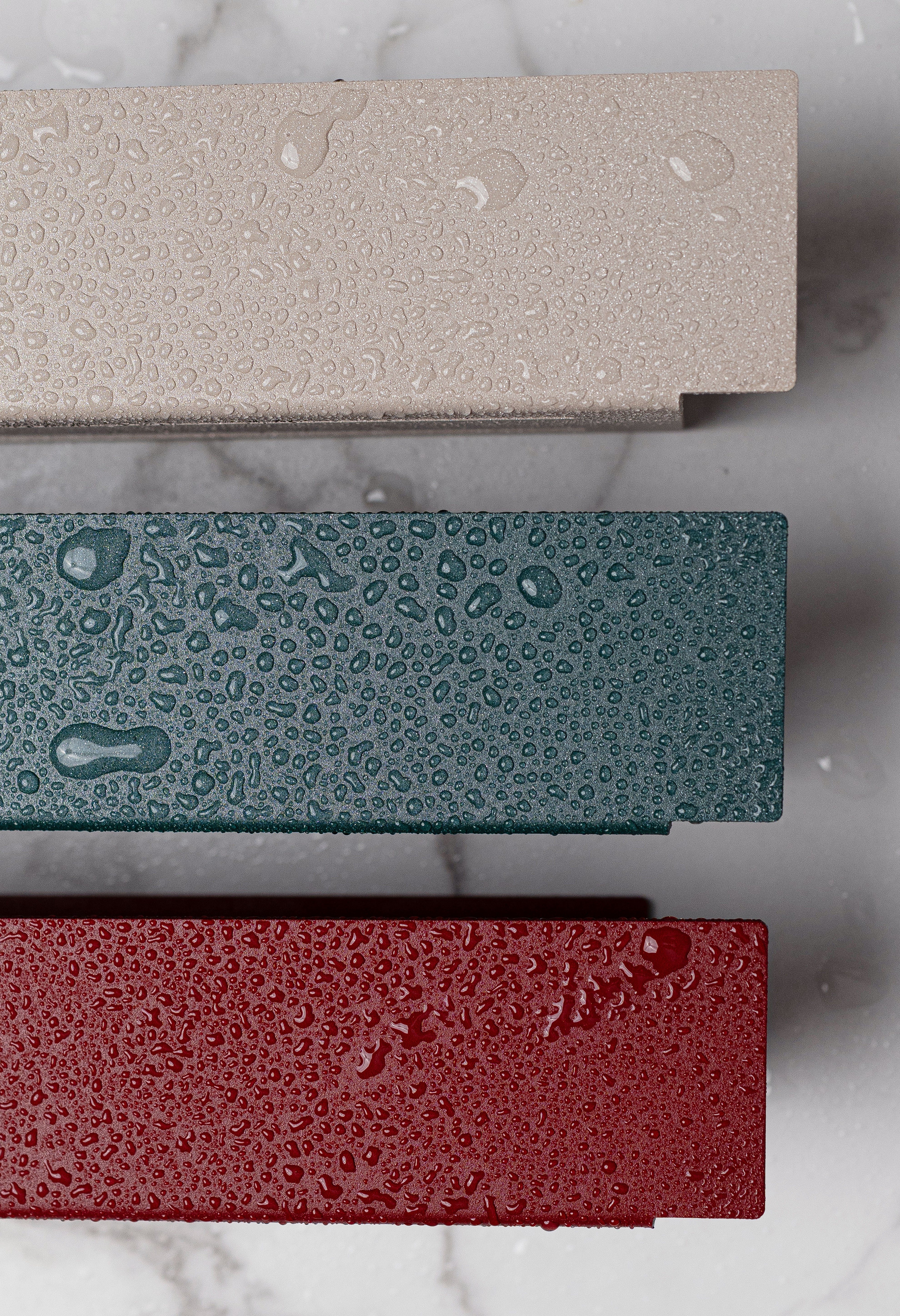 Close Up Duschablage Korsika zum Kleben in Farbe Champagner, Sparkling Green und Velvet Red. Wassertropfen perlen auf der pulverbeschichteten Oberfläche ab.