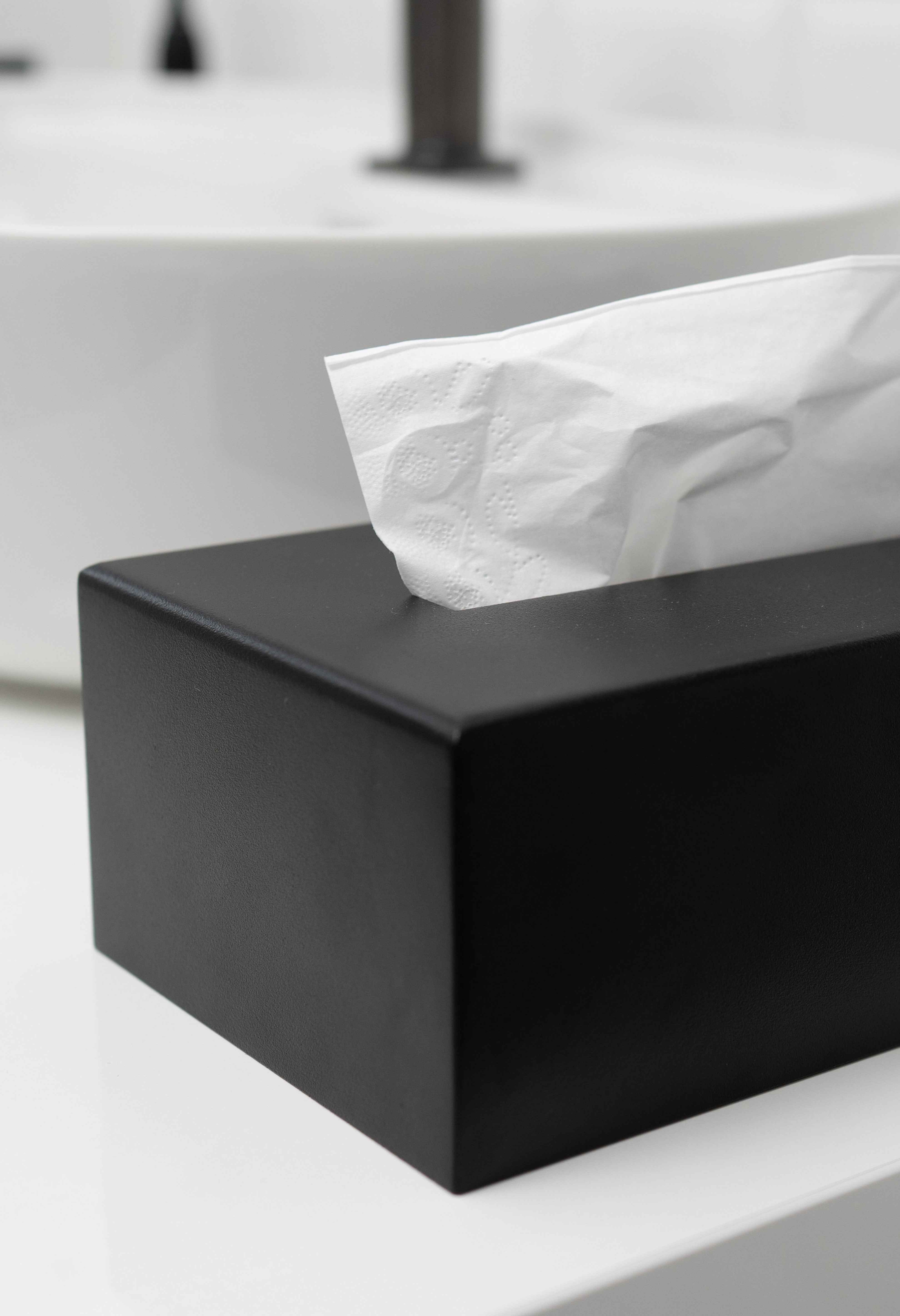 Kosmetiktuchbox in schwarz auf in einem hellen weißen Bad. Nahaufnahme der Pulverbeschichtung und Kante.