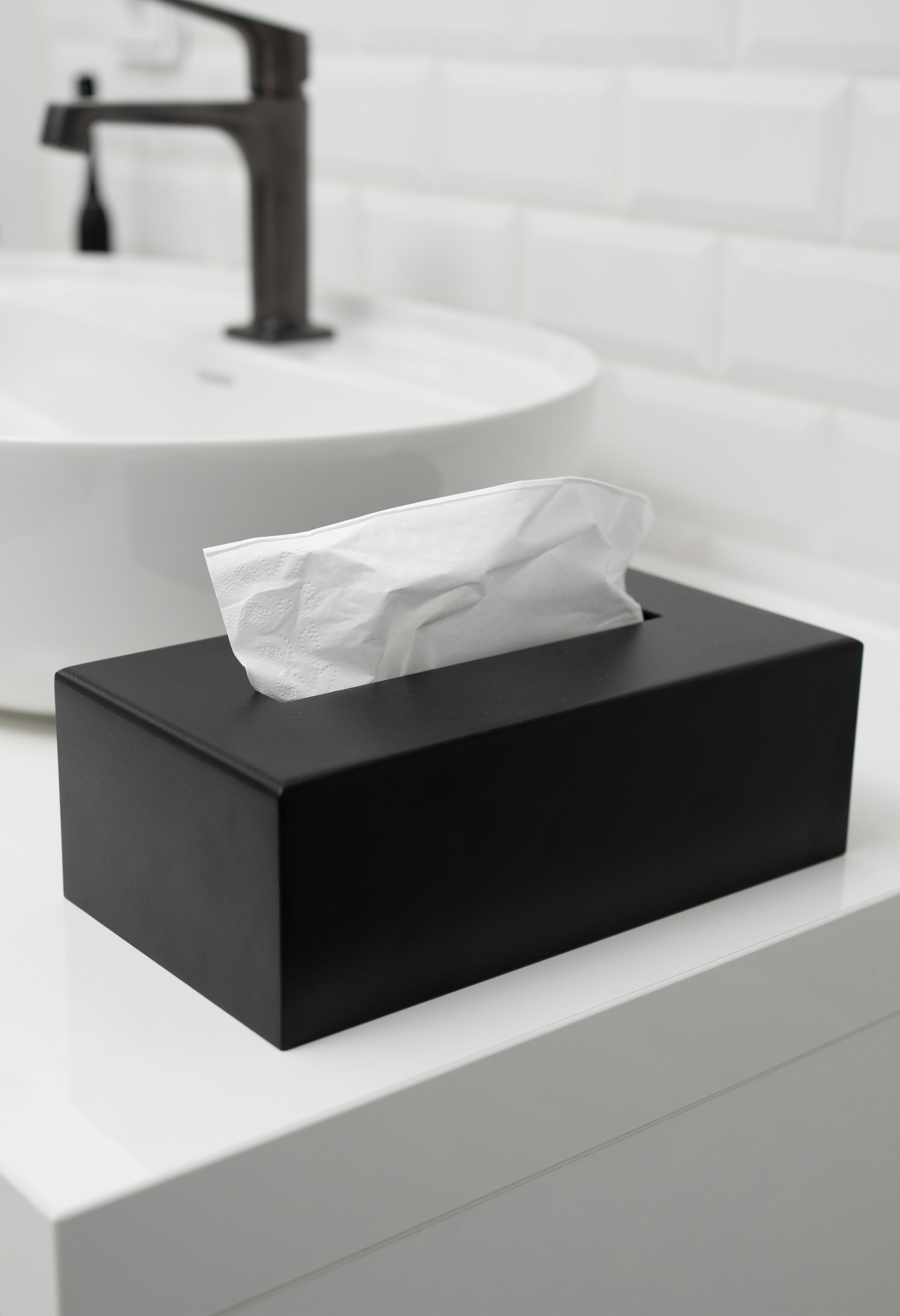 Kosmetiktuchbox in schwarz auf in einem hellen weißen Bad.