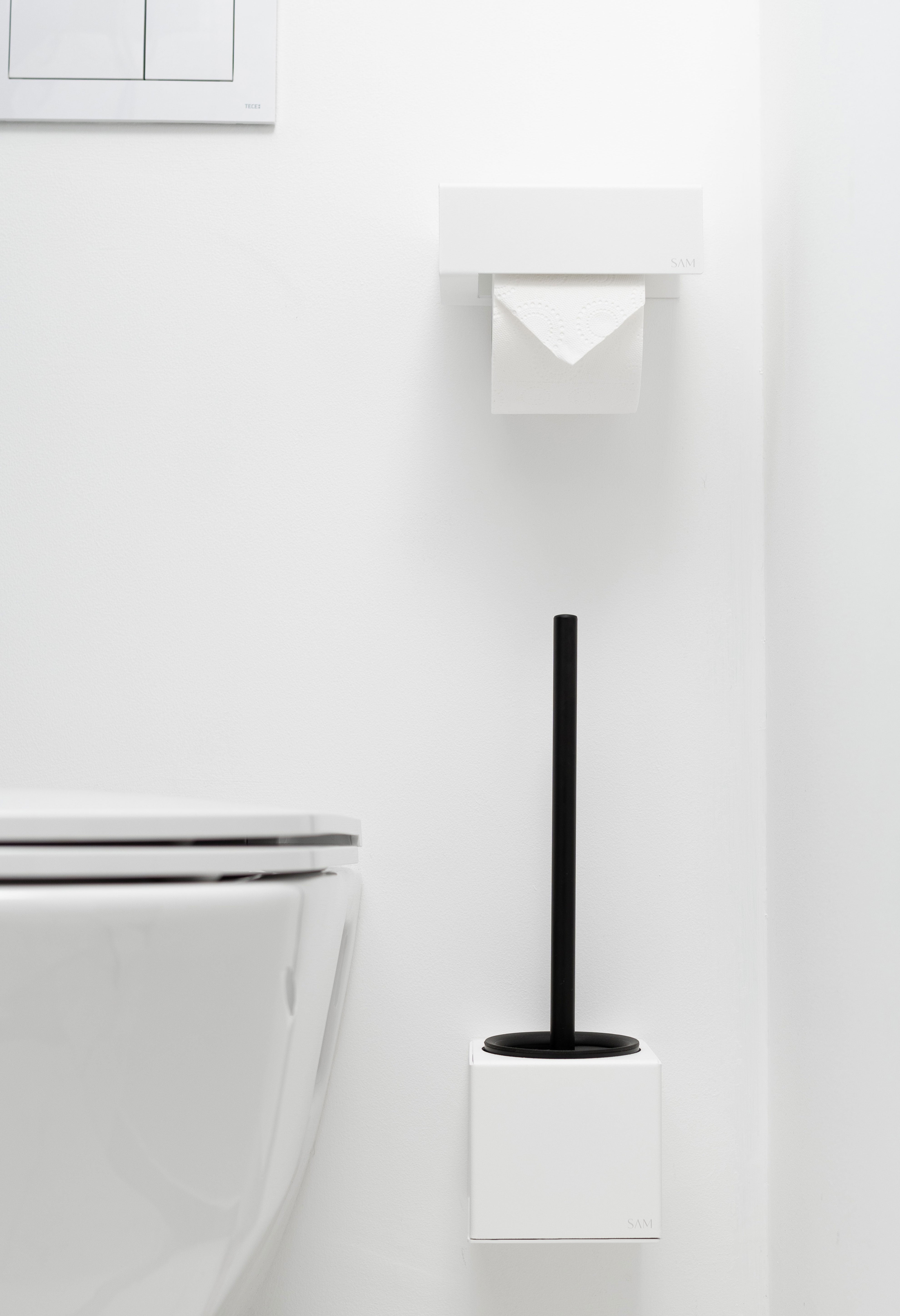 WC-Bürstenhalter LYON aus pulverbeschichtetem Stahl zum Kleben ohne Bohren in Farbe weiß mit passendem Toilettenpapierhalter ohne Bohren darüber in frotnalo Ansicht