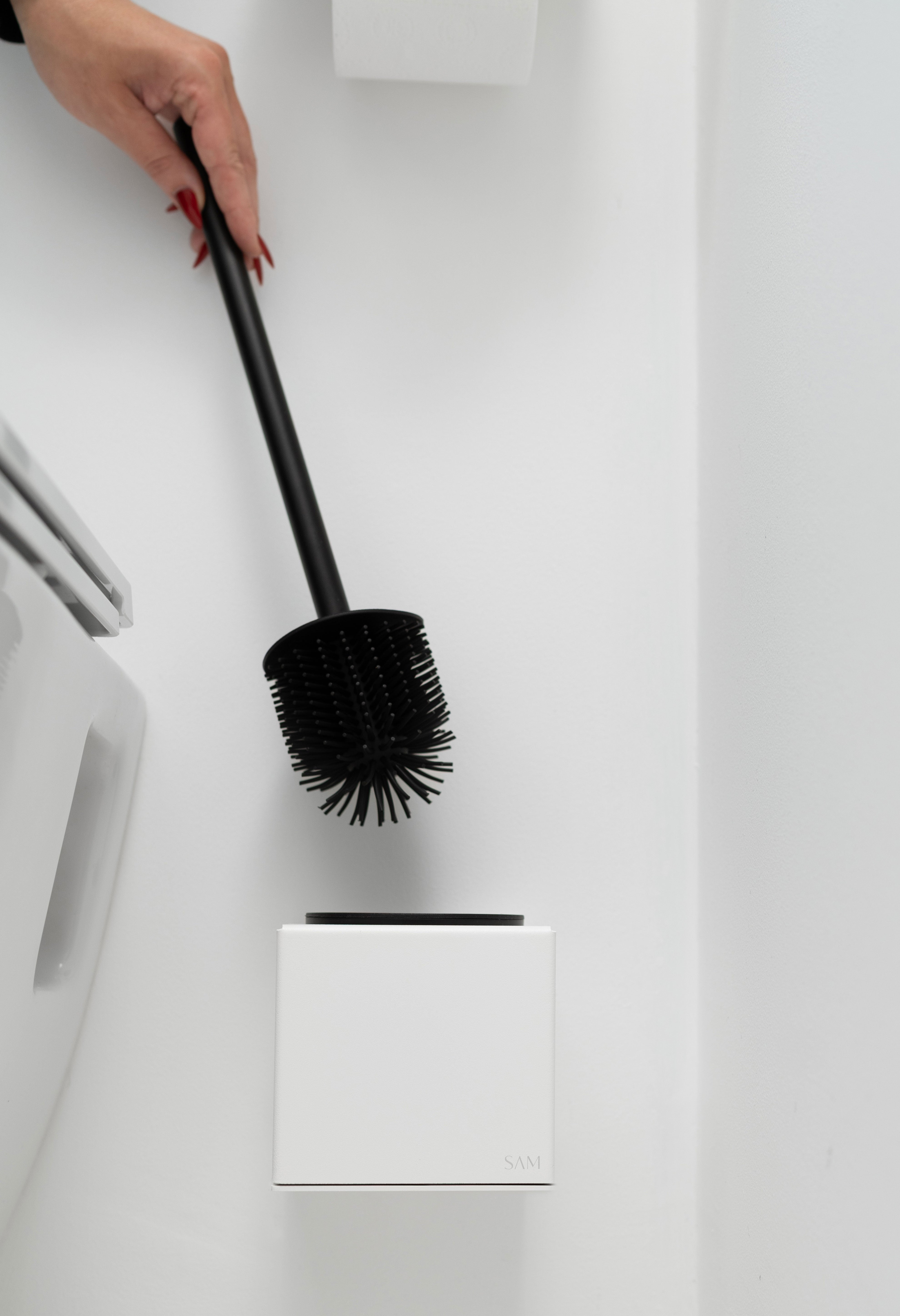 WC-Bürstenhalter LYON aus pulverbeschichtetem Stahl zum Kleben ohne Bohren in Farbe weiss mit Hand die die WC-bürste herauszieht